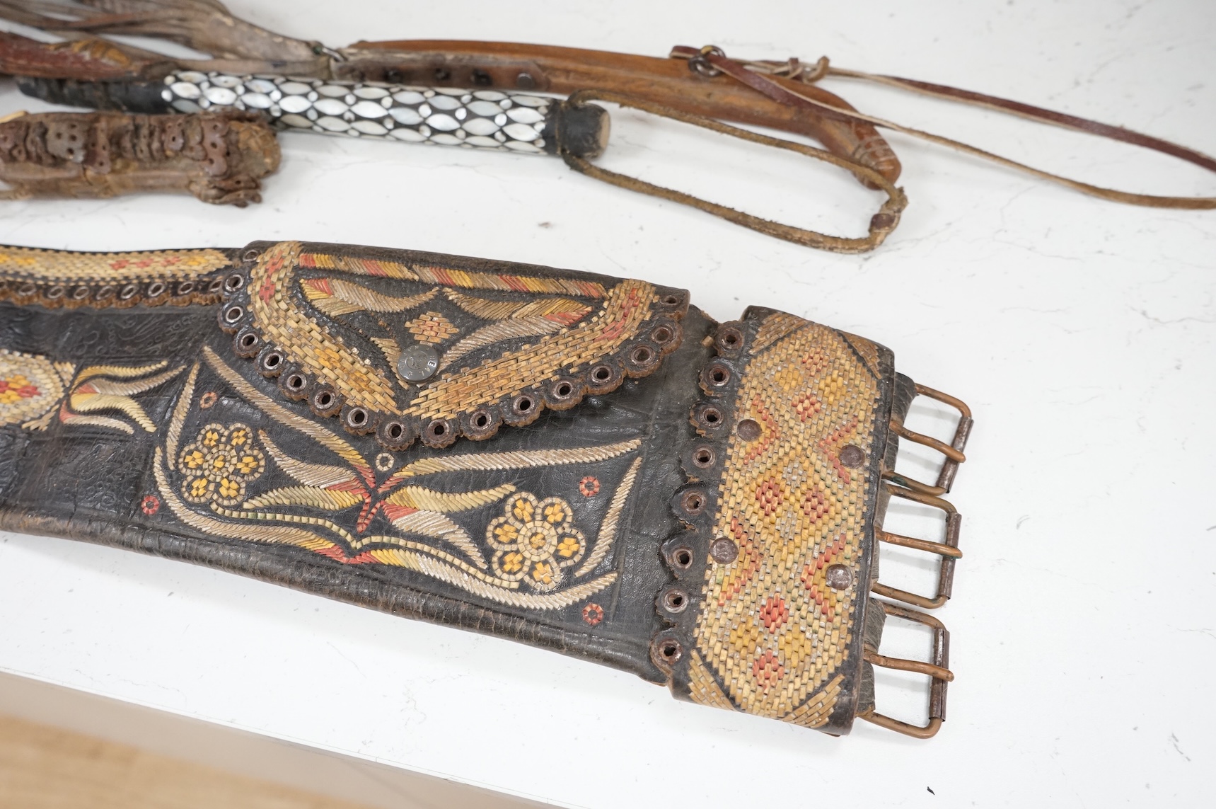 An Argentinian braided leather belt and whips, one with mother of pearl inlay
